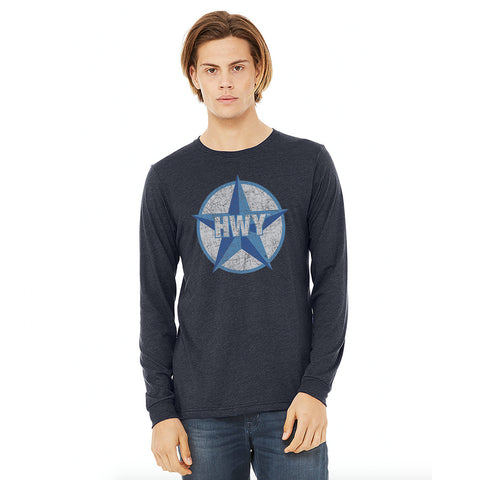 A guy wearing a Vintage Heather Navy Long Sleeve T-Shirt with a two toned blue graphic of the Blue Star Highway logo on it.