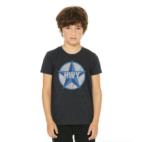 A kid wearing a Charcoal T-Shirt with a two toned blue graphic of the Blue Star Highway logo on it.