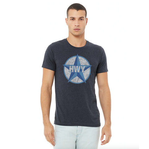 A guy wearing a Vintage Heather Navy T-Shirt with a two toned blue graphic of the Blue Star Highway logo on it.