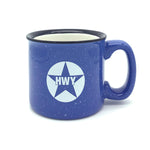 A blue ceramic coffee mug with a white circle and the letters HWY printed on it leaving a blue star design showing through.