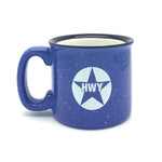 A blue ceramic coffee mug with a white circle and the letters HWY printed on it leaving a blue star design showing through.